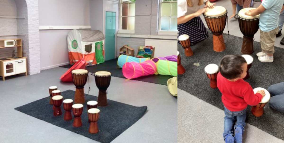 A room with drums toys, with a child in red sweater and jeans playing with drums in a playroom