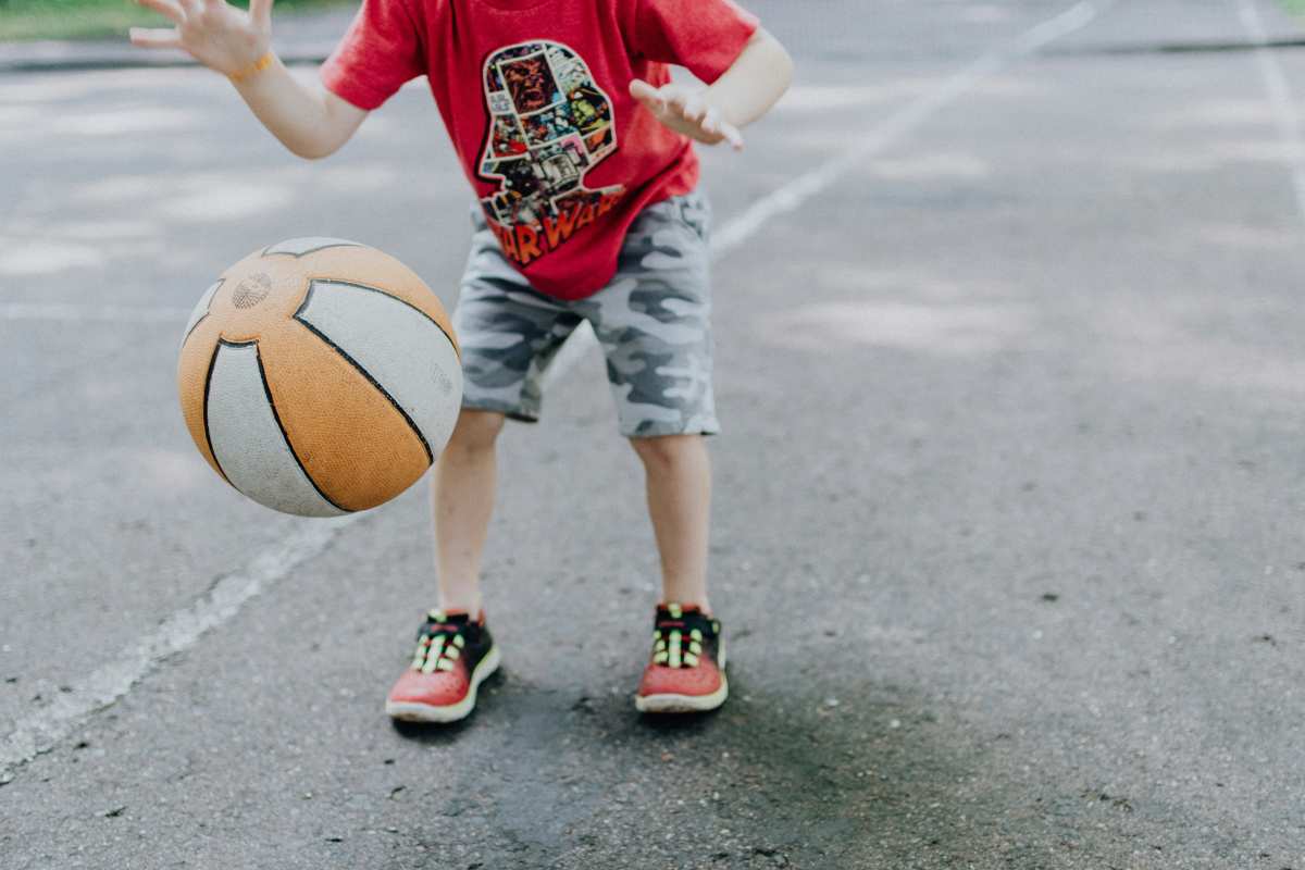 A child bouncing a basketball on pavement