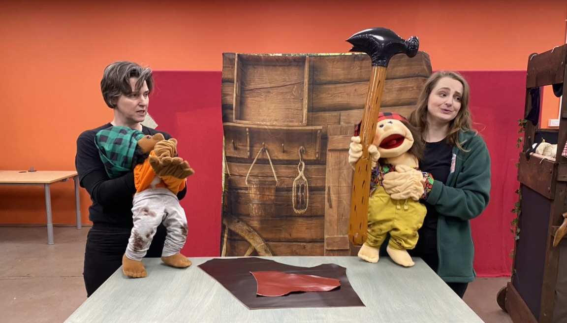 2 women with a large puppet each on stage during a theatre performance