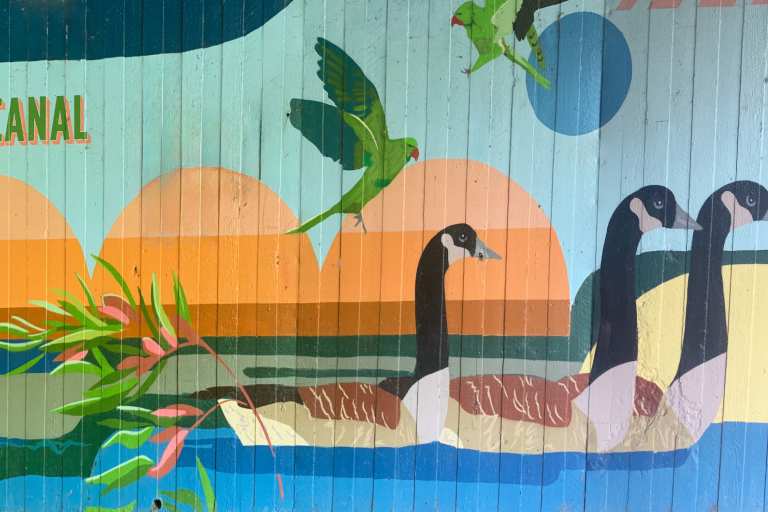 Mural on wall of geese on canal, parakeets, beaver and heron on land in trees