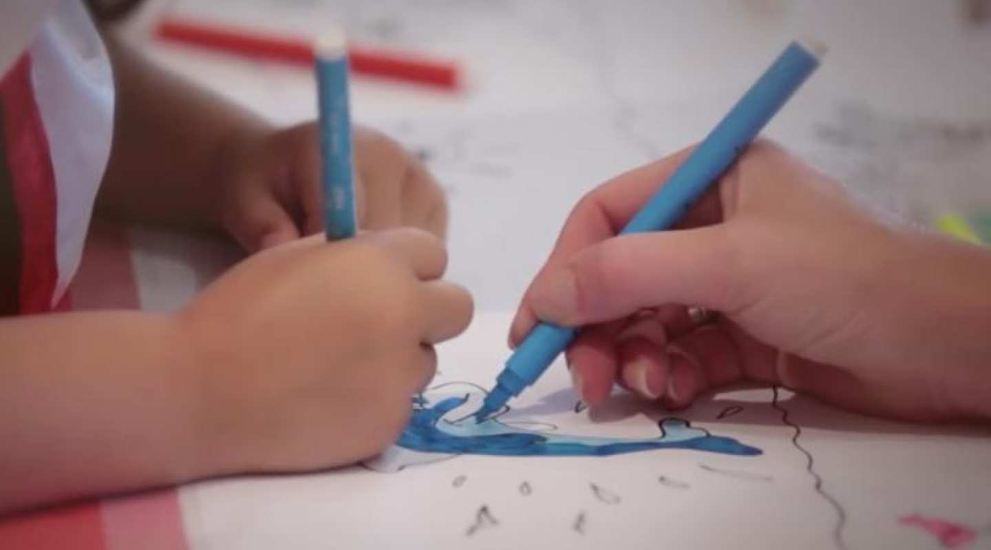 Hands of child and adult drawing and colouring