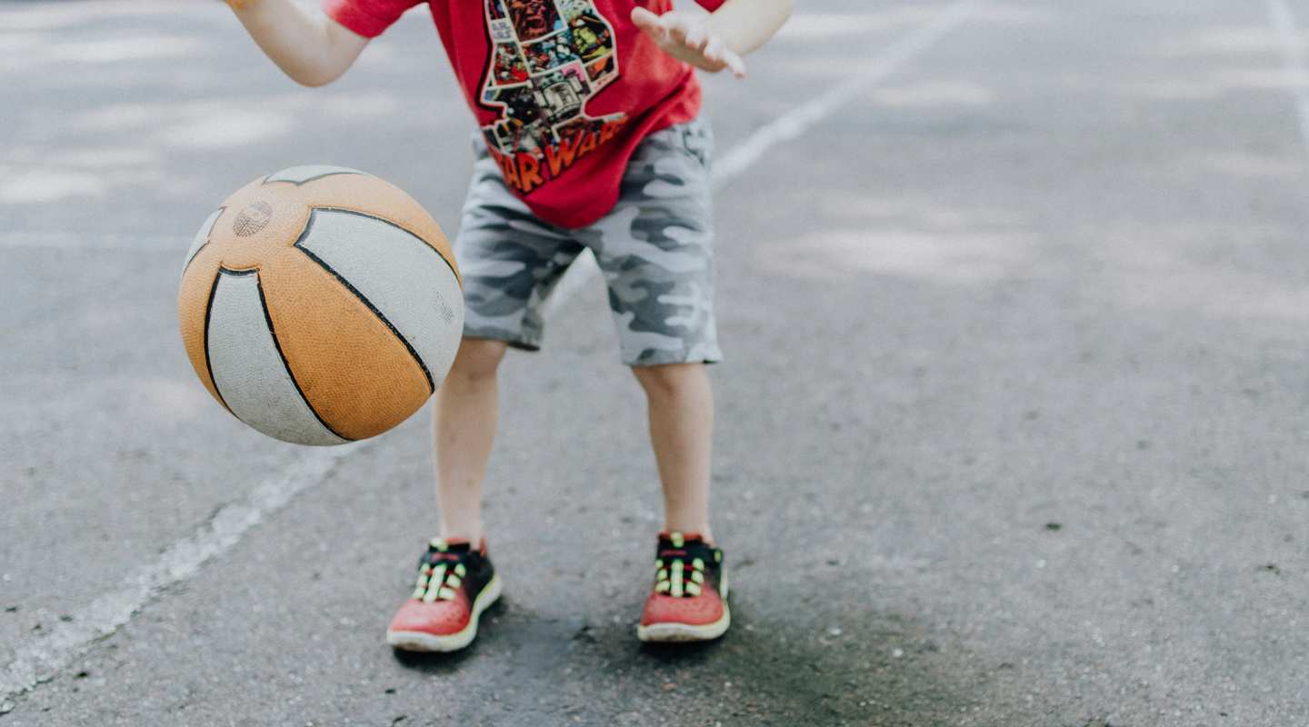 A child bouncing a basketball on pavement